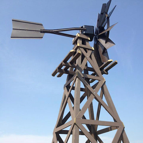 Wooden windmill on tall timber tower against blue sky
