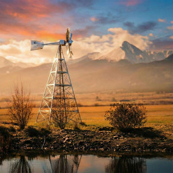 Metal farm windmill in a mountain landscape at sunset.