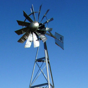 A silver windmill including the top of the windmill frame on a blue sky background.