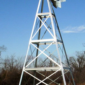 Close up of a silver 4-legged windmill head against a blue sky.