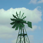 A green windmill on blue sky background.