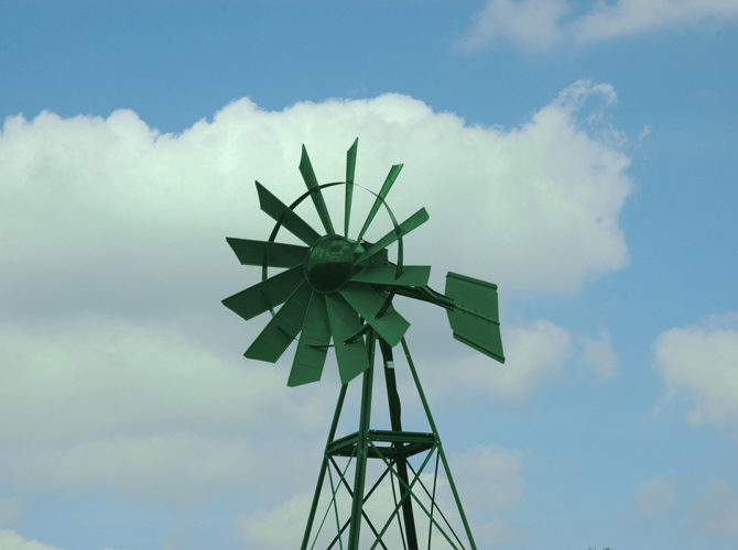A green windmill on blue sky background.