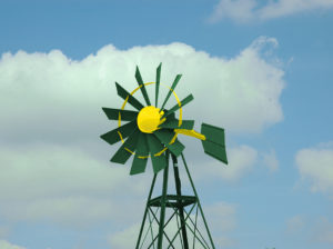 A green and yellow windmill on a blue sky.