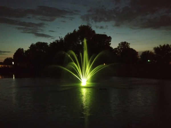 A single floating fountain lit up with LED lights creating a brilliant light display at night.