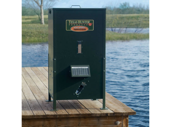 A 250 pound Texas Hunter Fish Feeder on a dock by a pond.