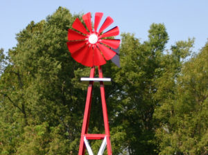 Large Backyard Windmill in red with trees in the background.