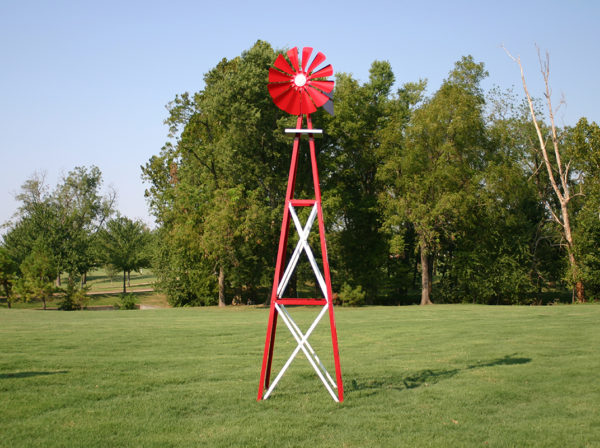 Full image of a Large Backyard Windmill in red with trees in the background.