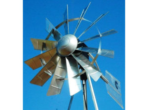 A silver windmill head against the blue sky.