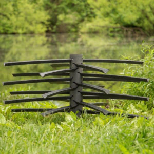 Close up of a Root Wad Kit Fish Attractor with a stalk and a dozen arms. It is a compact Fish Attractor. It is set on the bank of a pond on green grass surrounded by trees.