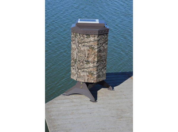 A camo fish feeder with a small solar panel on top at the end of a dock.