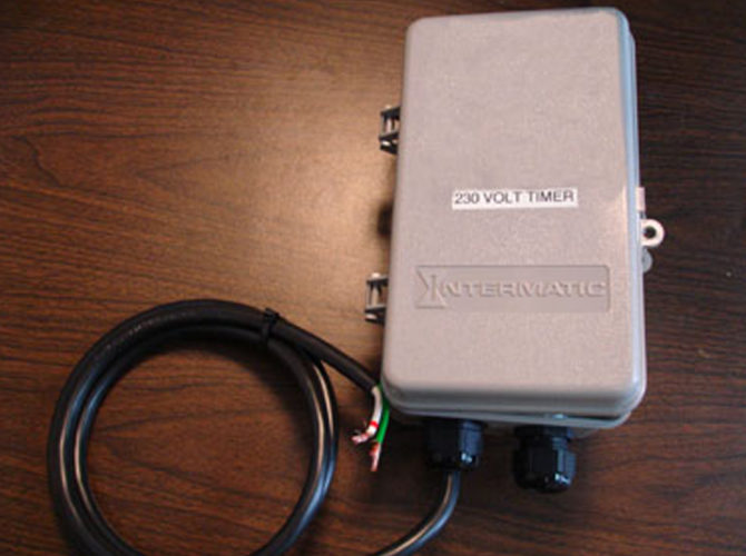 Close up on a timer for a floating pond fountain. There are black wires coming out of the bottom of the timer.