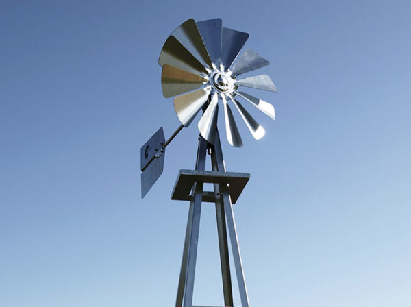 A silver windmill fan and tail fin against a blue sky.