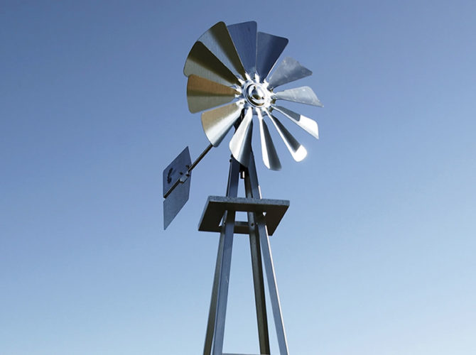 A silver windmill fan and tail fin against a blue sky.