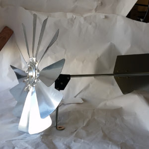 A silver windmill head and tail fin on a white paper background.