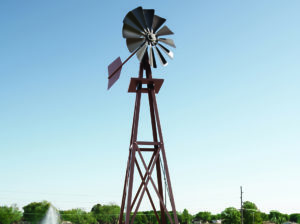 Upward angle of a small bronze windmill against a blue sky.