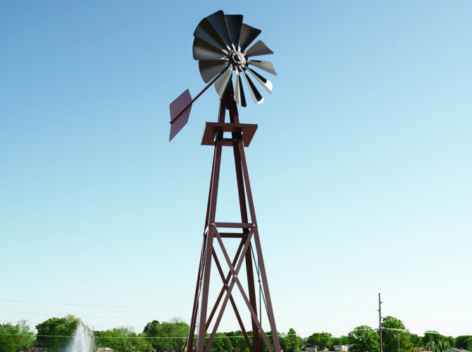 Upward angle of a small bronze windmill against a blue sky.