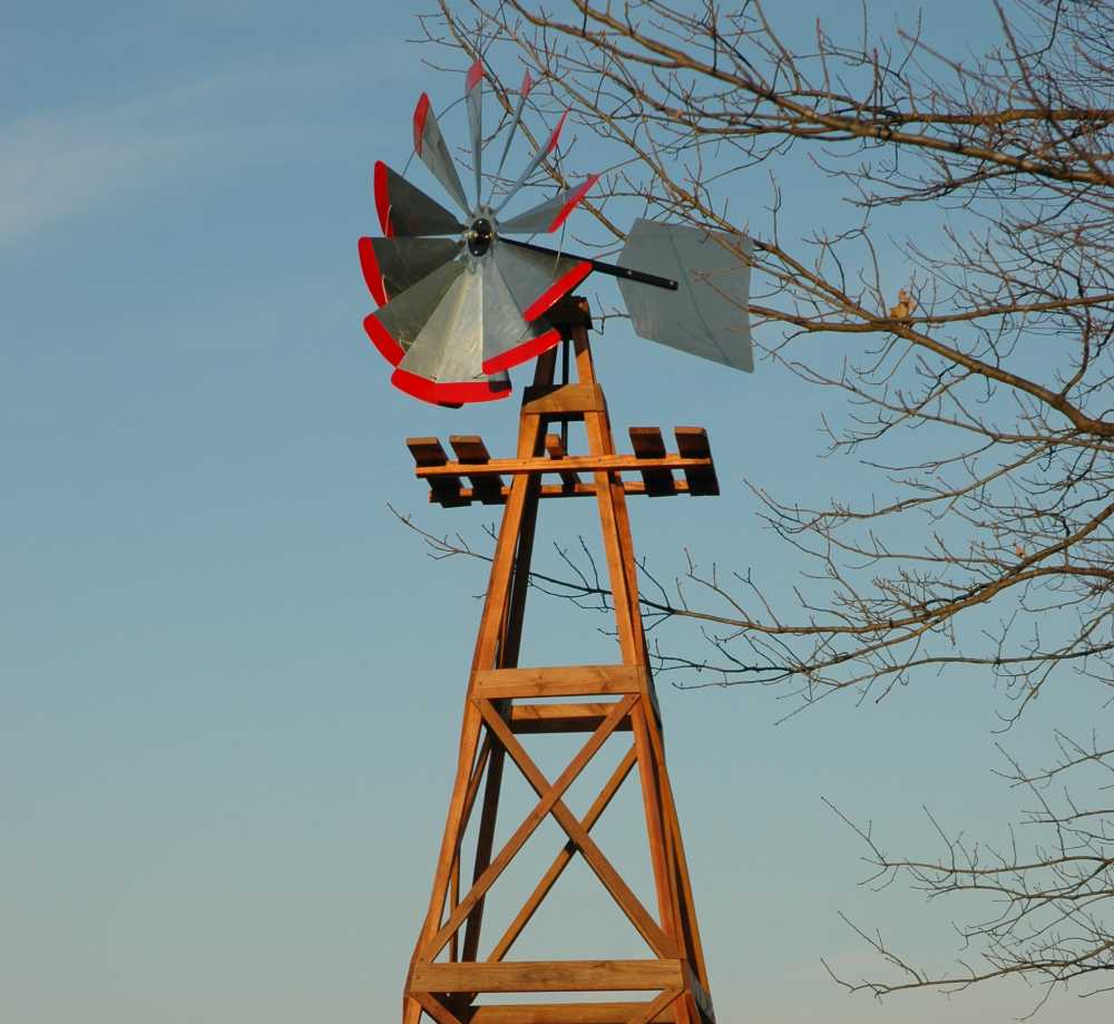 Silver windmill head with a red tips. The whole thing is on a wooden windmill.