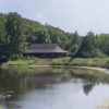 Pond with a building in the background. There are green trees surrounding the building.