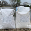 Two bags of Soilfloc Pond Sealant on the bank of a pond.
