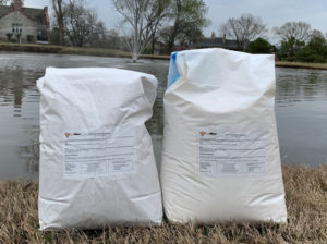Two bags of Soilfloc Pond Sealant on the bank of a pond.